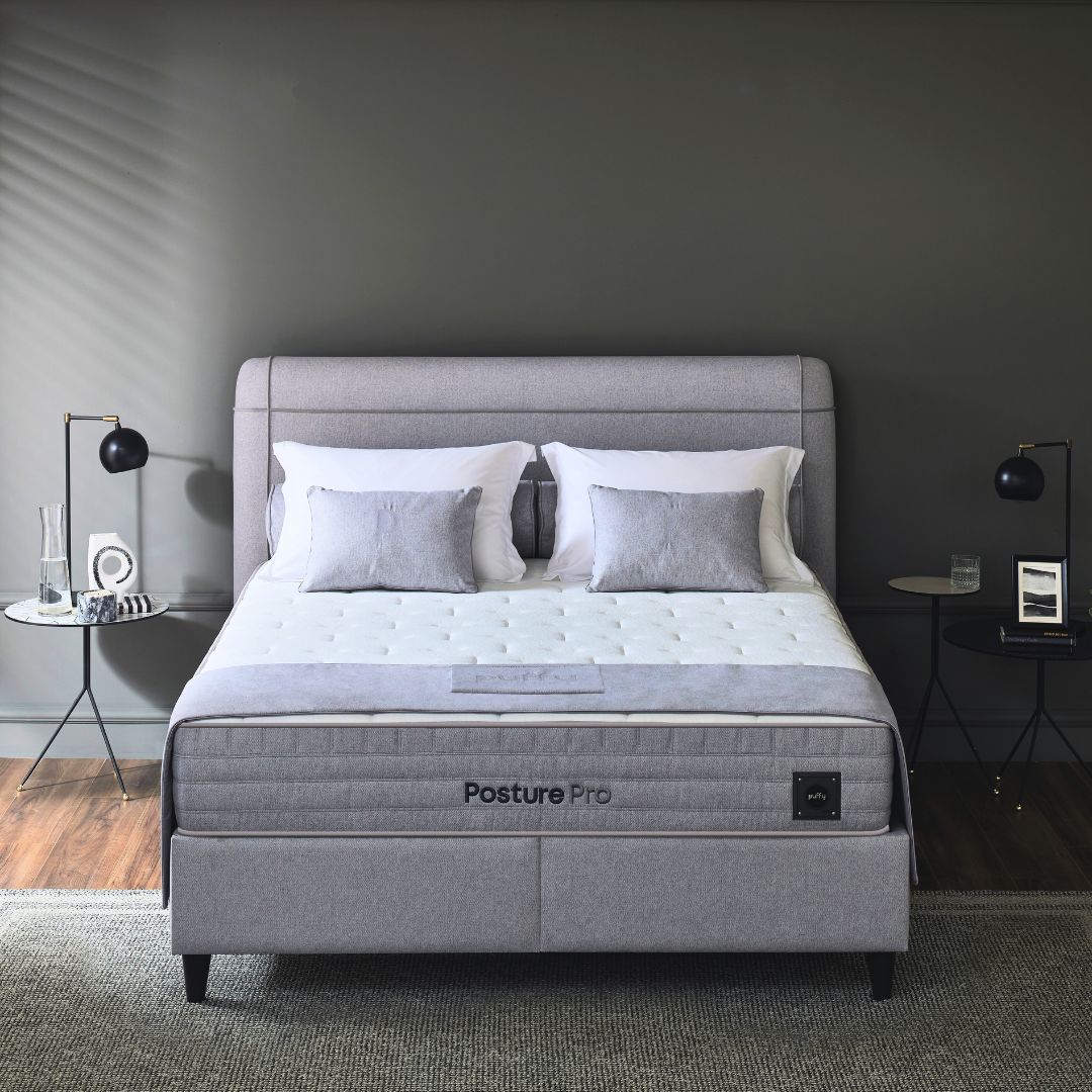 Профилен изглед на легло с включен матрак Puffy Posture Pro със сива тапицирана табла