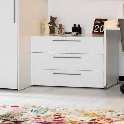 Детски скрин Neo с 3 чекмеджета в бял цвят, поставен до гардероб. Изглежда изчистено и поддържа стаята подредена.