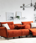 a living room with an orange couch and a potted plant
