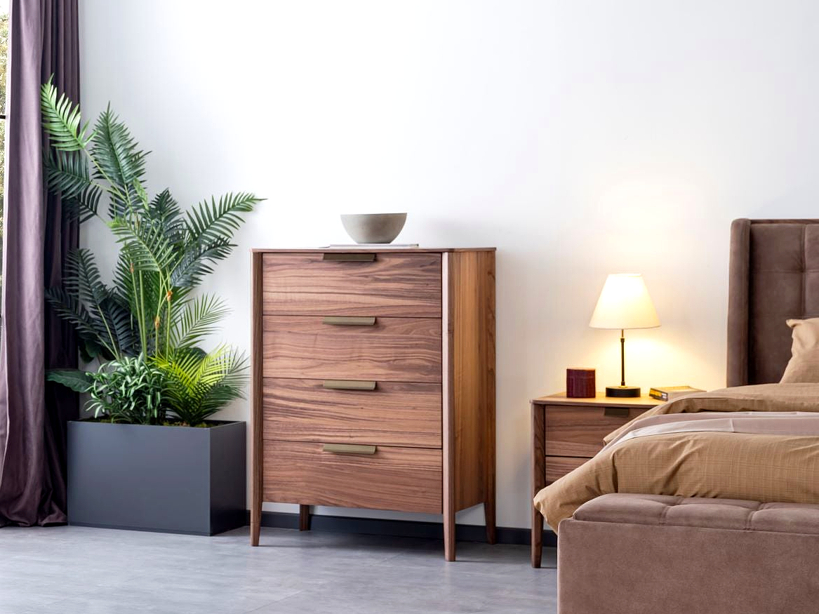 a bedroom with a bed, dresser and a plant